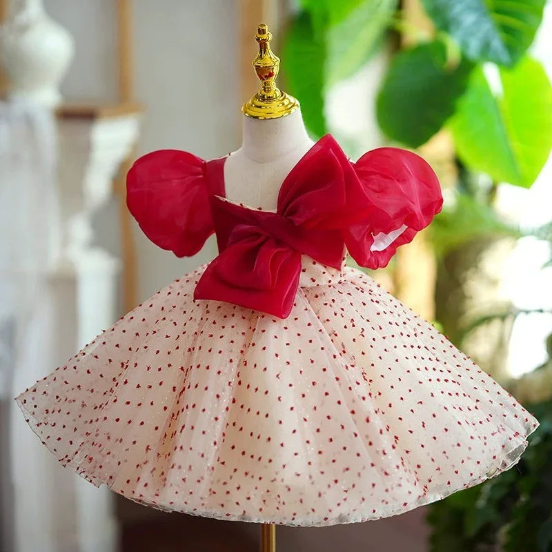 Elegant kids dress with red puff sleeves, large bow, and white skirt with red polka dots on mannequin