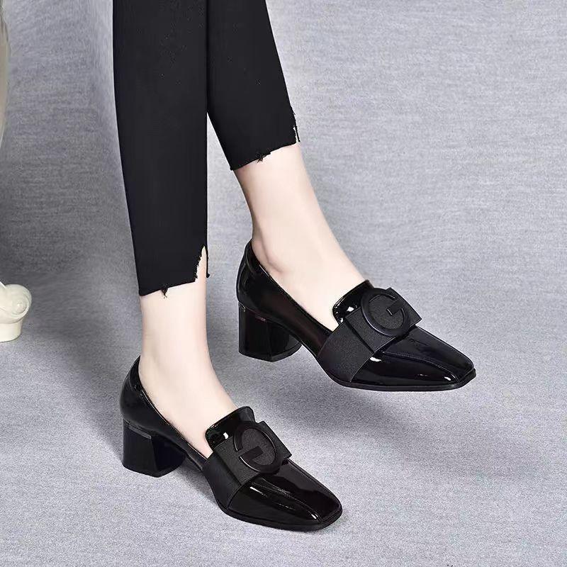 Glossy black block heel women's shoes with rounded buckle detail worn with black ankle-length pants