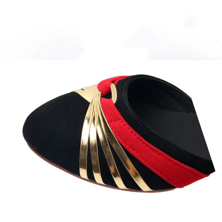 Black suede flat shoe with red trim and gold metallic strap details on white background