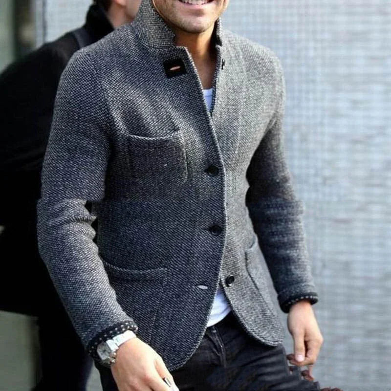 Man wearing a textured grey tweed blazer with black buttons and patch pockets over a white shirt