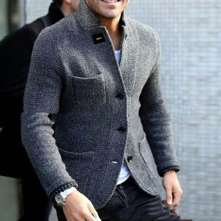 Man wearing a textured grey tweed blazer with black buttons and patch pockets over a white shirt