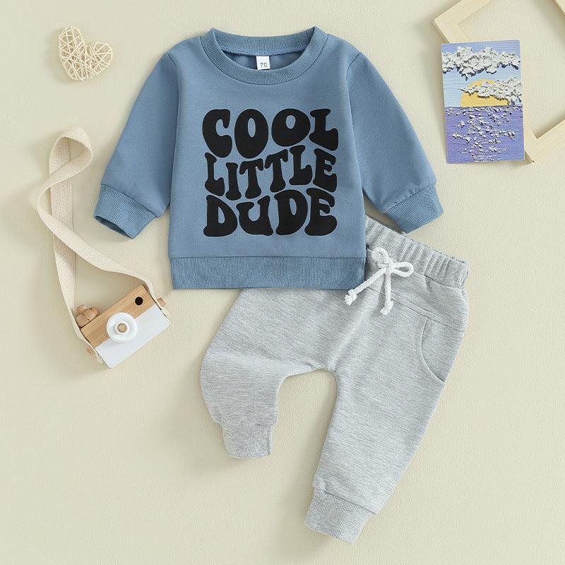 Blue toddler sweatshirt with 'COOL LITTLE DUDE' print and gray sweatpants set on beige background