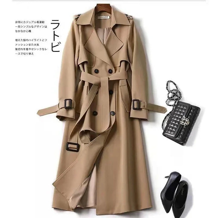 Beige double-breasted trench coat with belt, black quilted handbag, black pointed-toe heels on white background