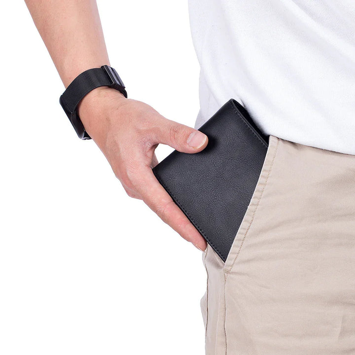Person inserting black leather wallet into beige pants pocket, wearing white shirt and black watch