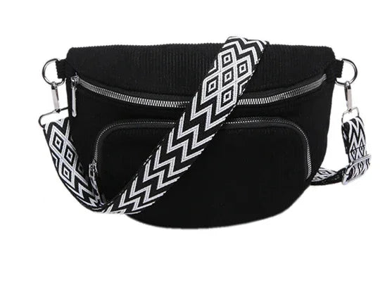 Black corduroy crossbody bag with silver zippers and detachable black and white geometric patterned strap