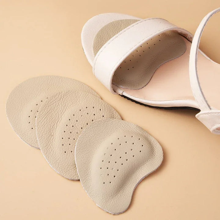 Beige leather shoe insoles with perforations beside a white sandal on a beige background