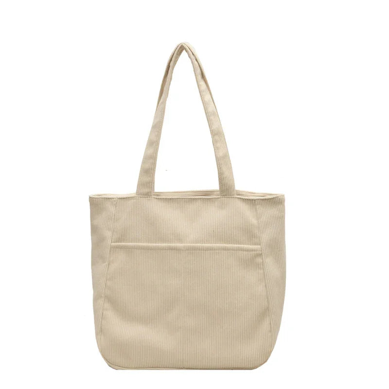Beige corduroy tote bag with long handles and front pocket on white background