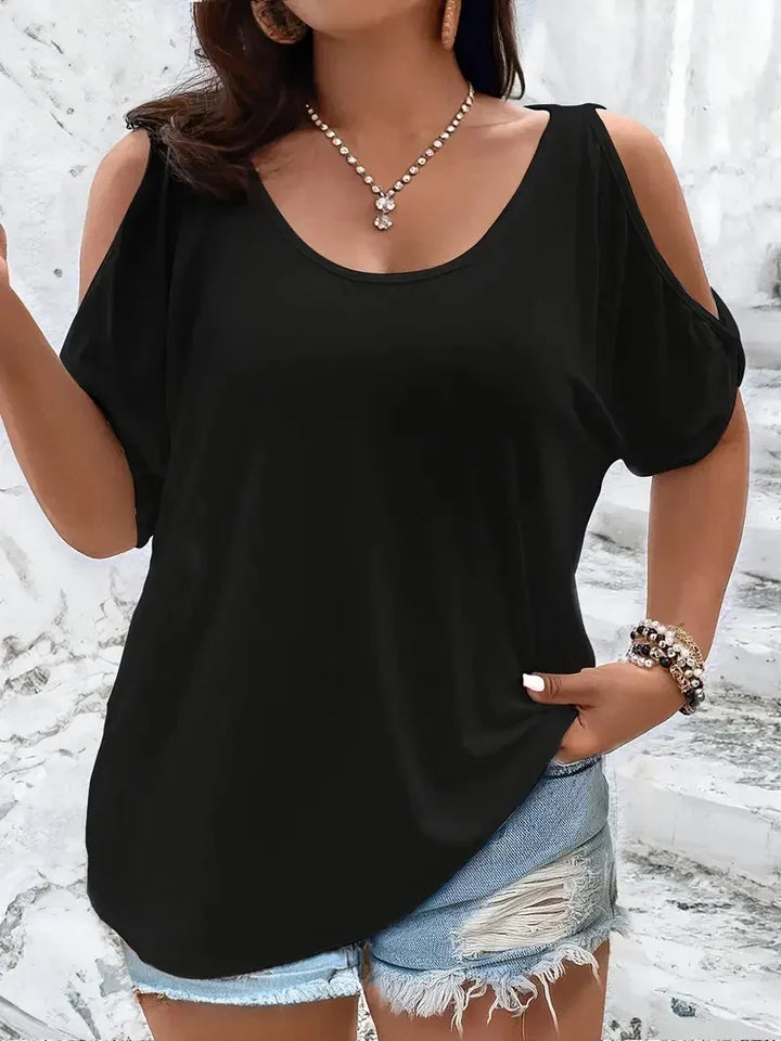 Woman wearing black cold-shoulder top with ripped denim shorts and pearl necklace