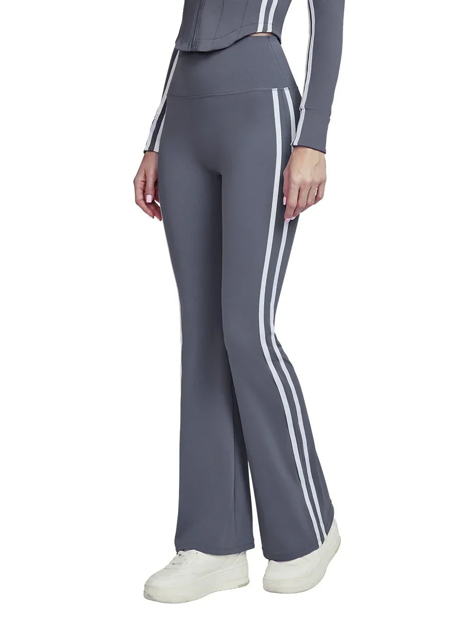 Woman wearing gray flared athletic pants with white side stripes and white sneakers