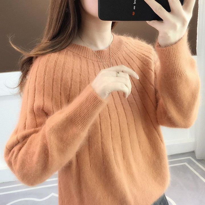 Woman wearing soft ribbed orange sweater taking selfie in neutral indoor setting