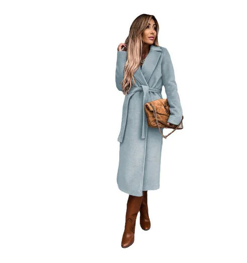 woman in light blue belted wool coat with brown boots and tan quilted handbag