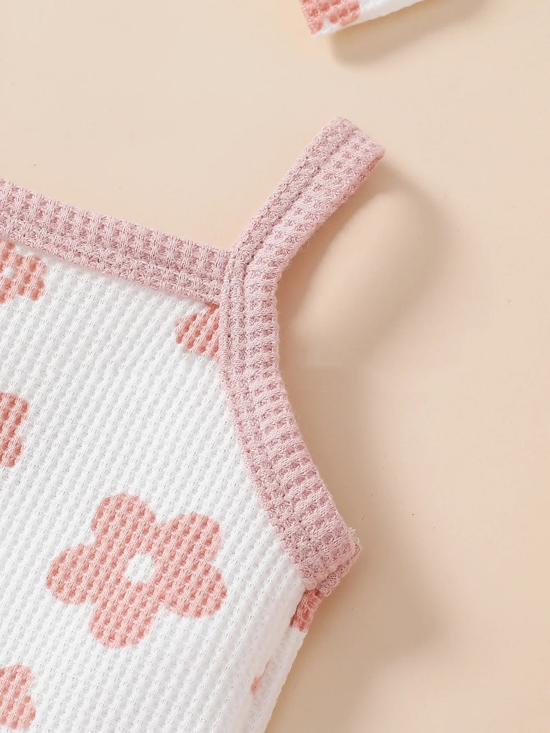 Close-up of white knit fabric tank top with pink floral pattern and pink ribbed straps