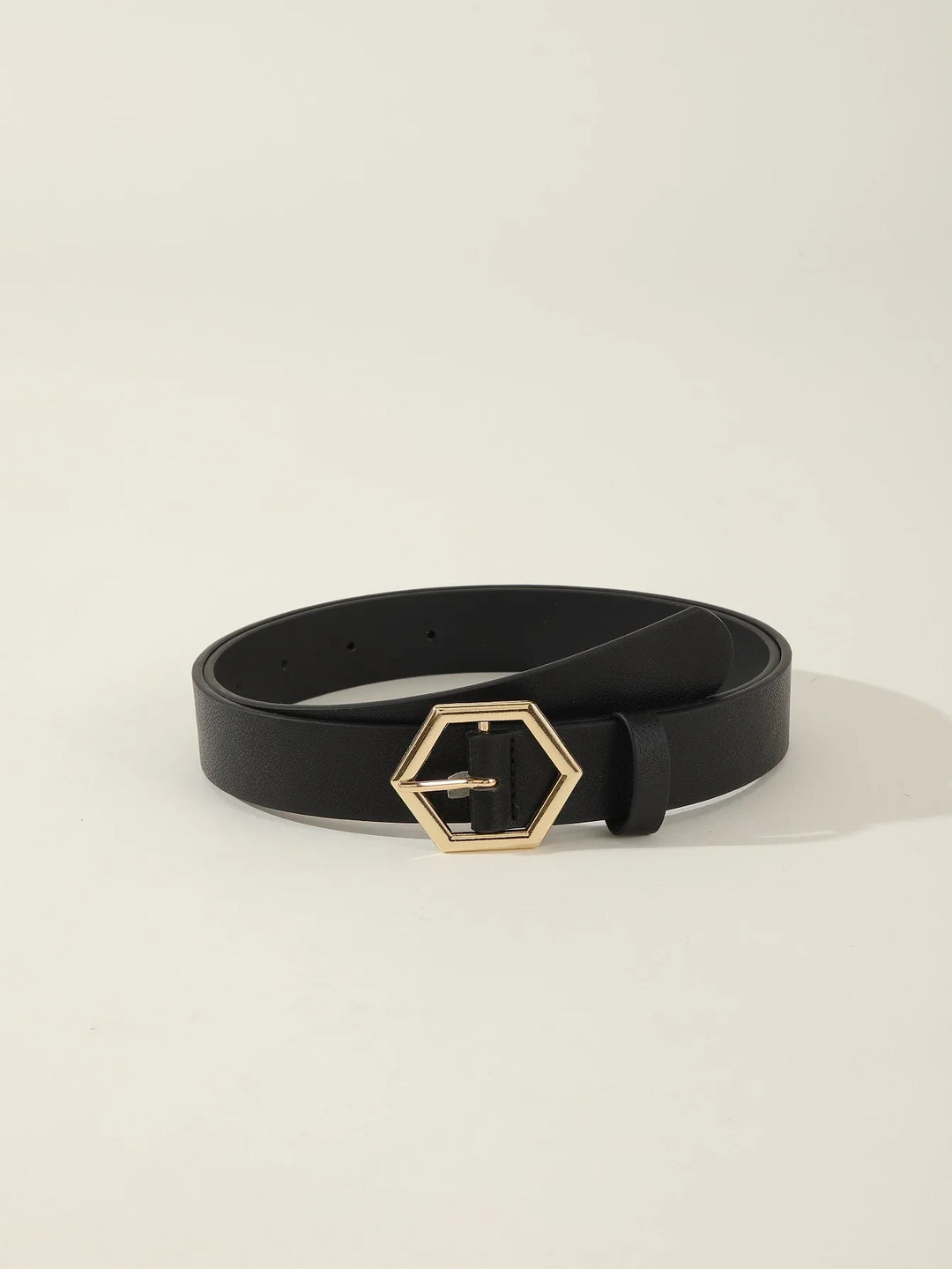 Black leather belt with gold hexagonal buckle on plain light background