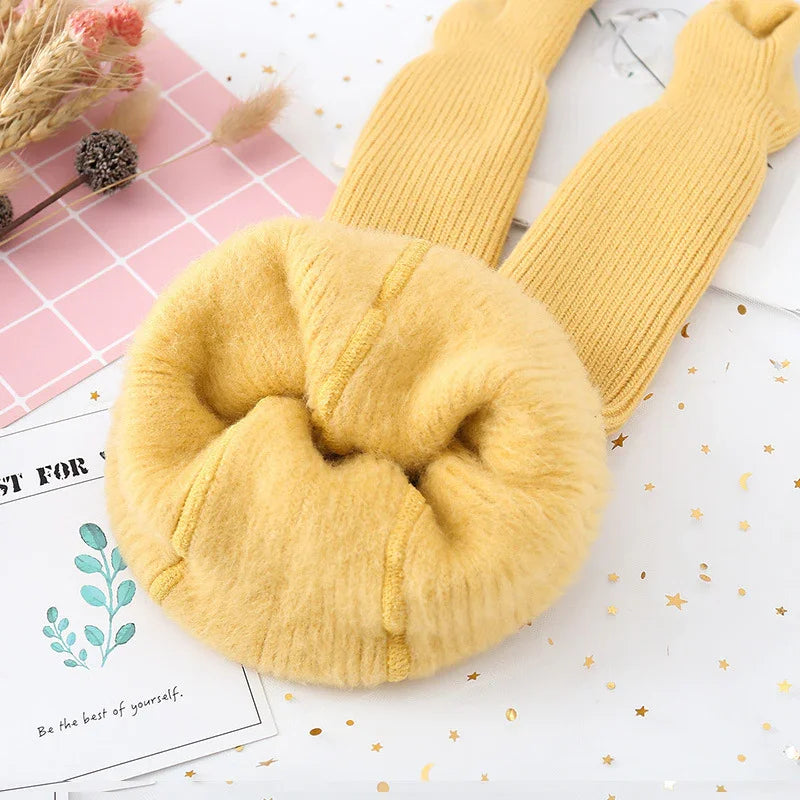 Yellow soft wool scarf with ribbed knit ends on decorative white and pink background