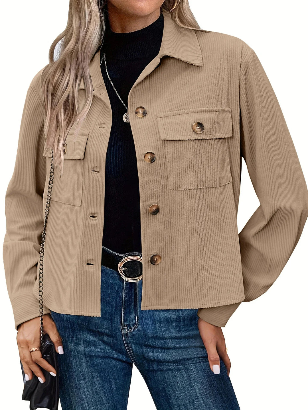 Woman wearing beige button-up corduroy jacket with flap pockets over black turtleneck and blue jeans