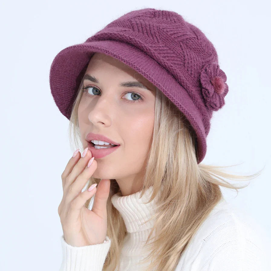 Young woman wearing a purple knit bucket hat with flower detail and a white turtleneck sweater