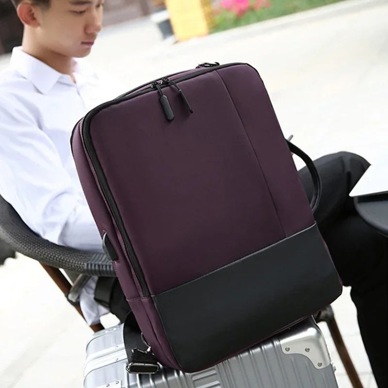Purple and black laptop backpack resting on silver suitcase with person seated in outdoor cafe
