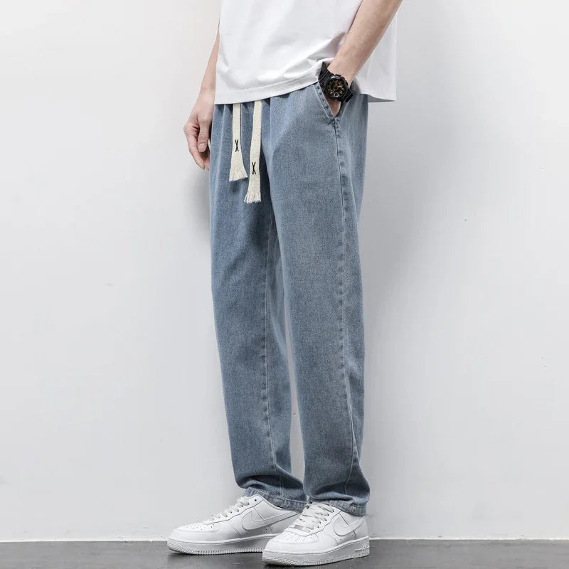 man wearing light blue denim jogger pants with white drawstring and white sneakers