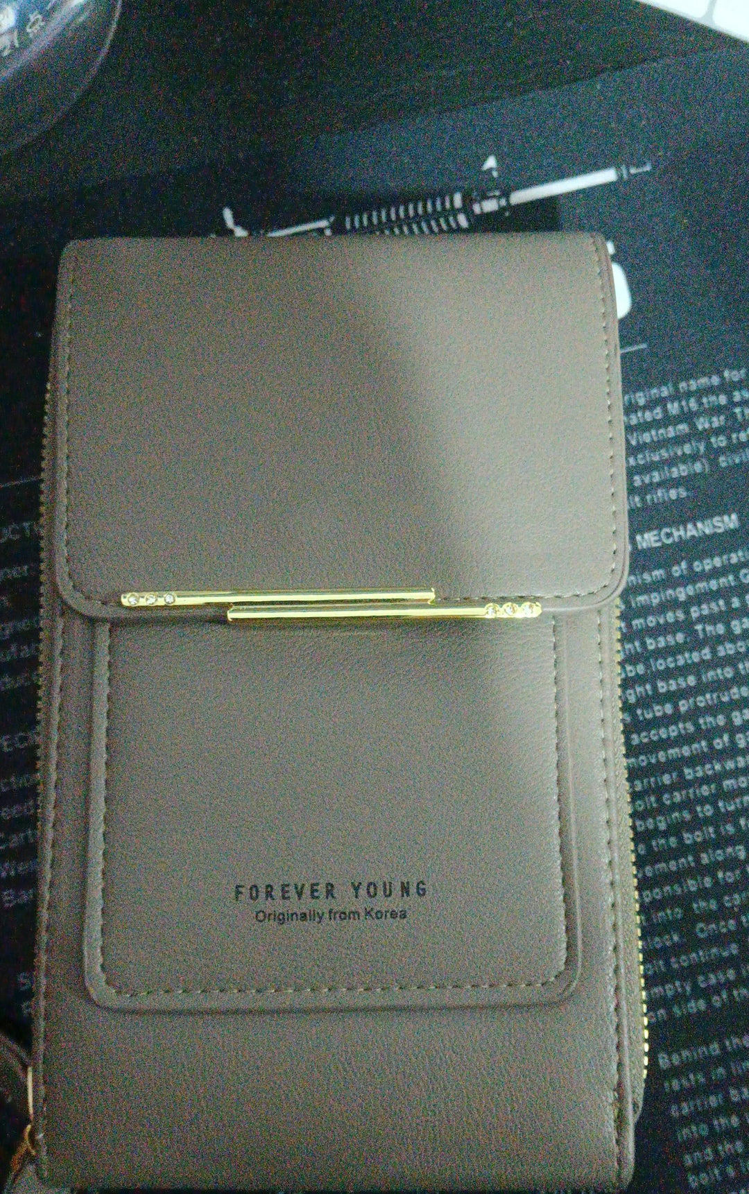 Gray Forever Young leather wallet with gold clasp on black printed background