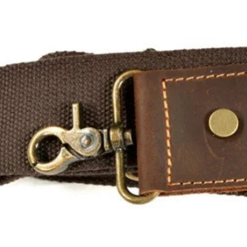 Close-up of brown canvas strap with brass swivel hook and stitched leather patch