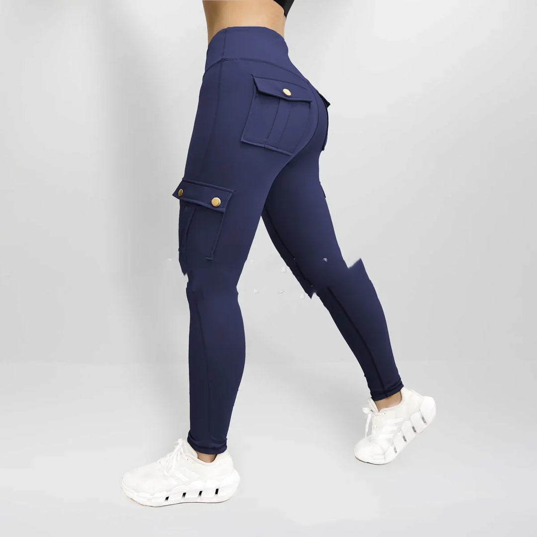Woman wearing navy blue cargo leggings with button pockets and white sneakers against a plain background