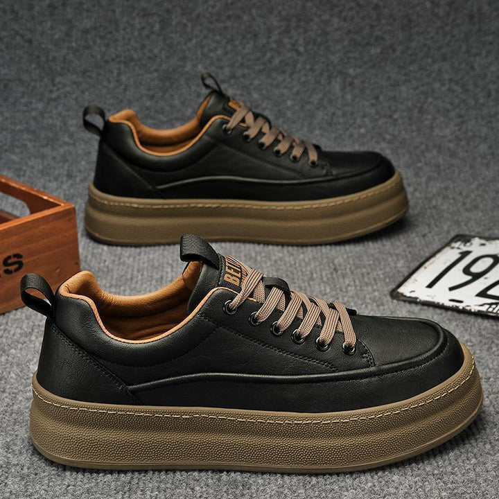 Black casual sneakers with brown thick soles and laces on gray carpet background