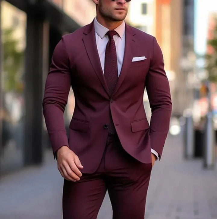 Man wearing a slim-fit burgundy suit with matching tie and white pocket square in an urban setting