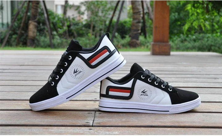 Pair of black and white Jiyuni casual sneakers with red and black stripes on wooden deck outdoors