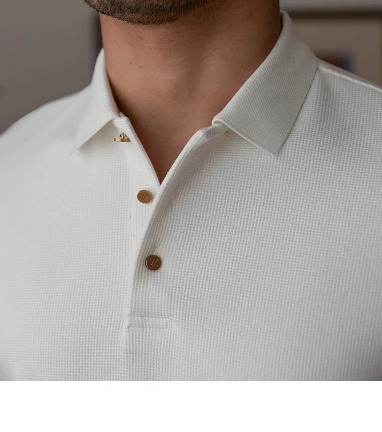Close-up of a man wearing a white textured polo shirt with gold buttons and a collar