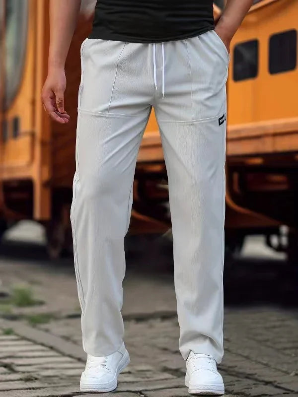 Man wearing white casual jogger pants with pockets and white sneakers in urban setting