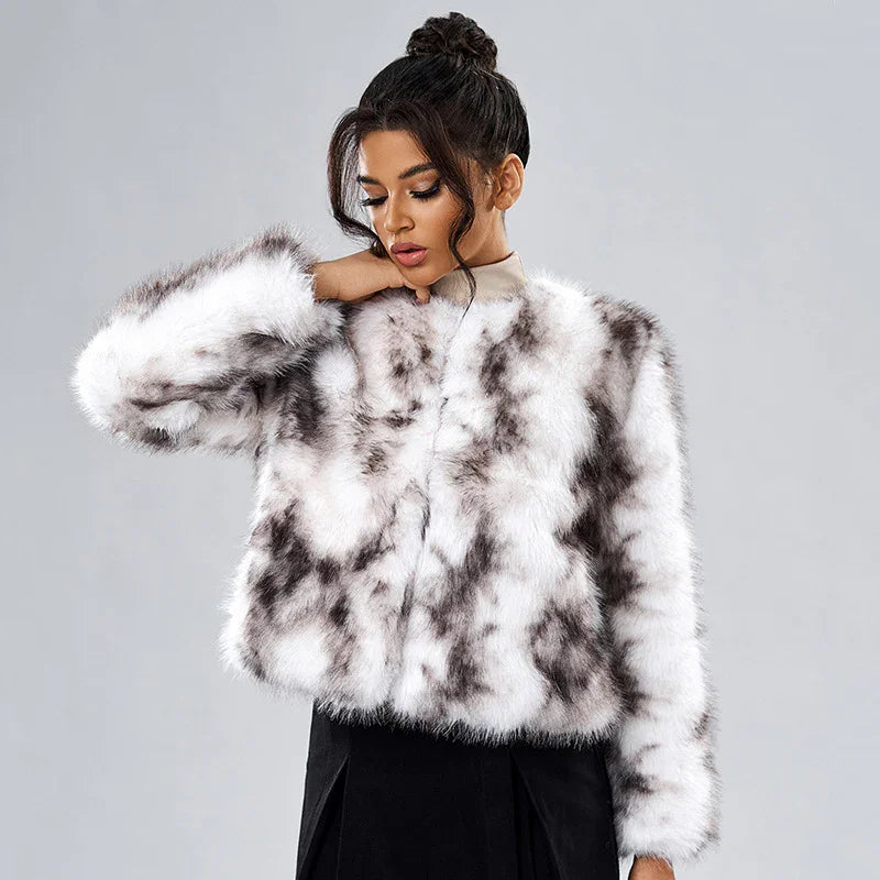 Woman wearing a stylish white and gray spotted faux fur jacket with a high collar against a gray background