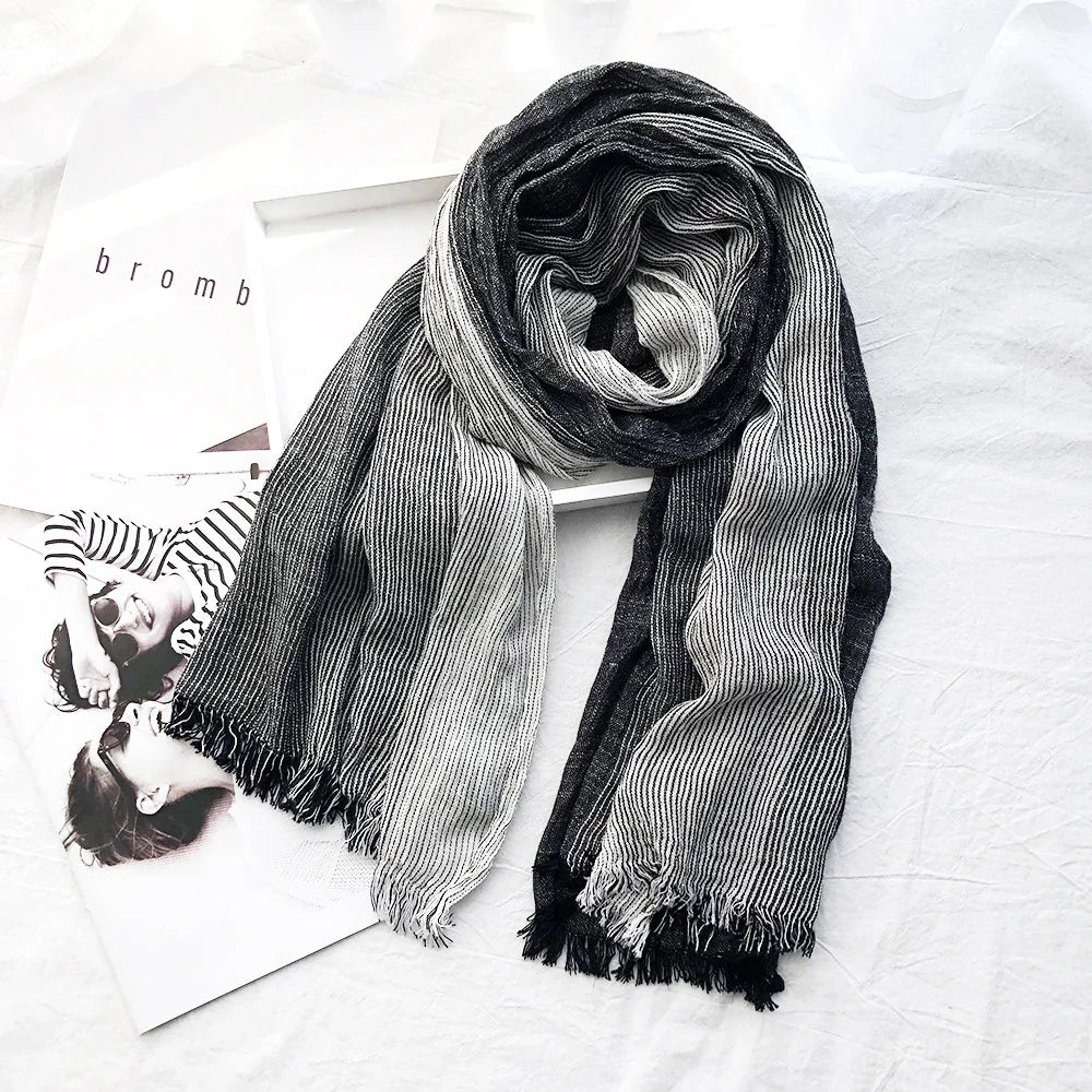 Black and white striped fringed scarf laid on white fabric with black and white magazine pages