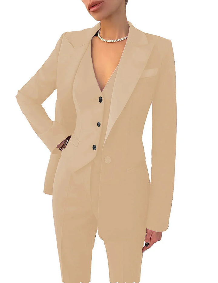 Woman wearing beige tailored suit with blazer, vest, trousers, and pearl necklace