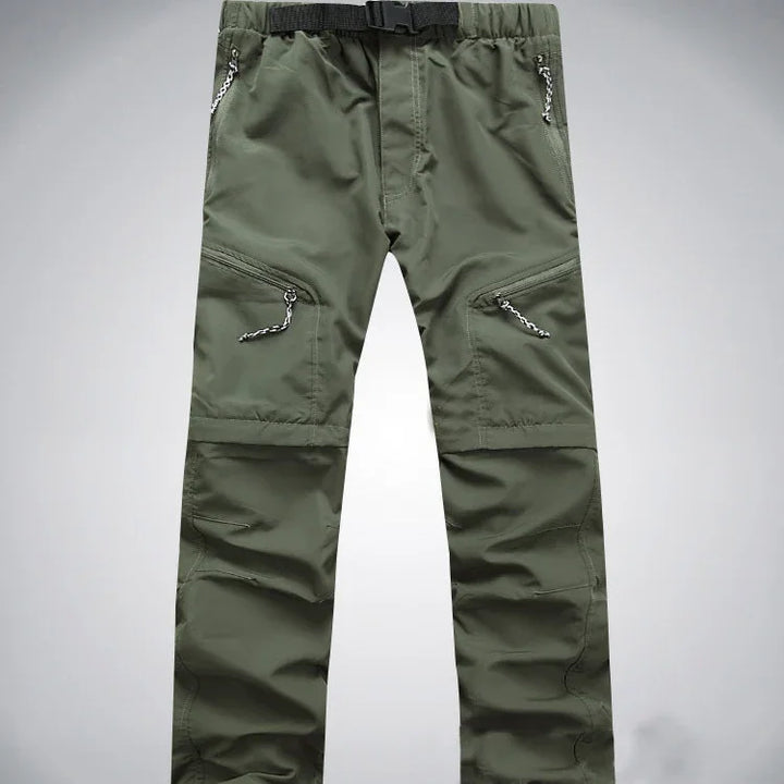 Green outdoor hiking pants with multiple zippered pockets and integrated belt on gray background