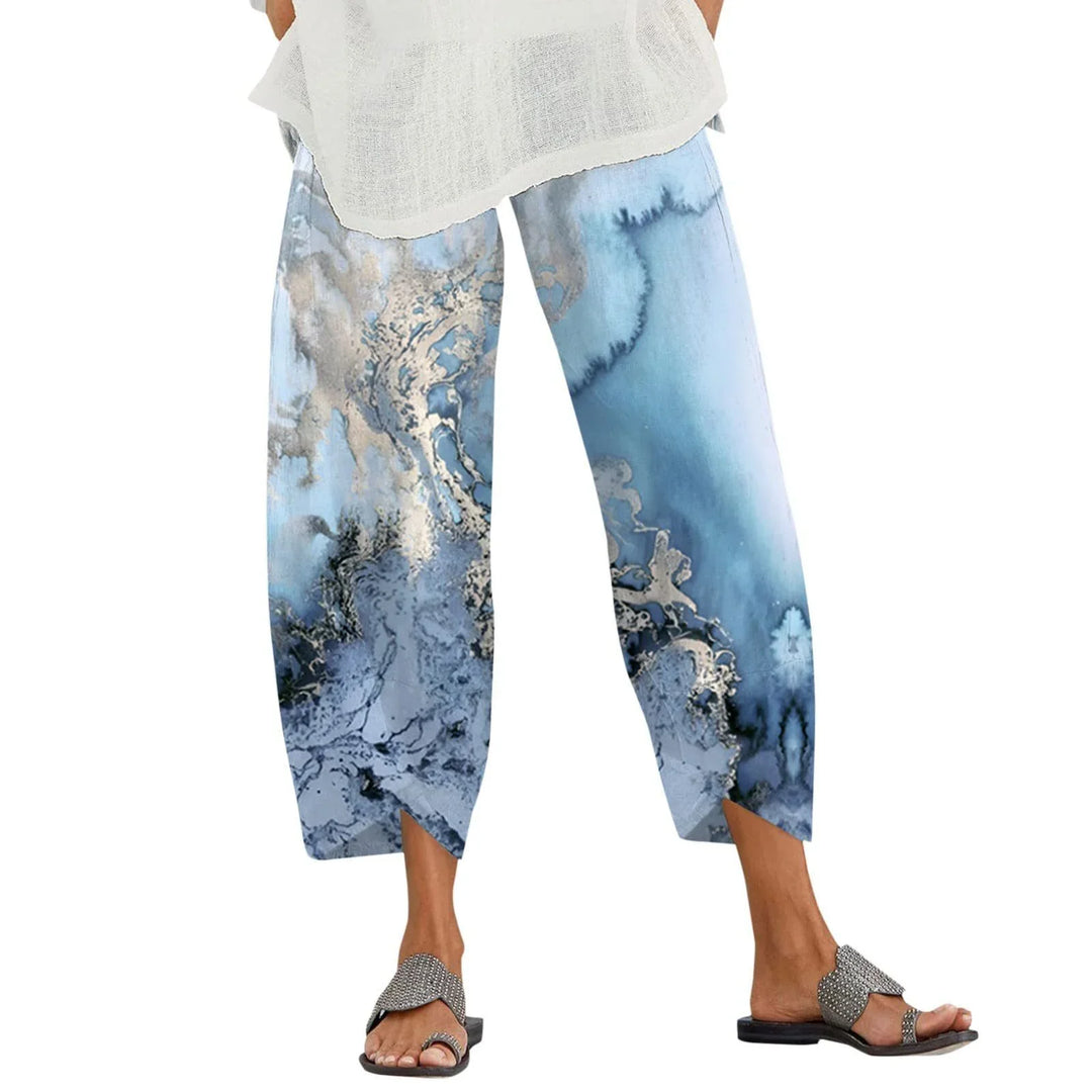 Woman wearing blue and white abstract print casual wide-leg pants with white top and silver sandals