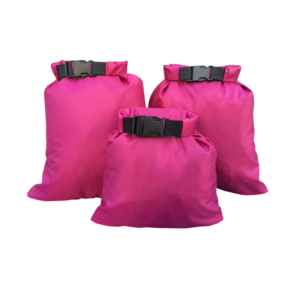 Three pink waterproof dry bags with black buckle closures, camping gear.