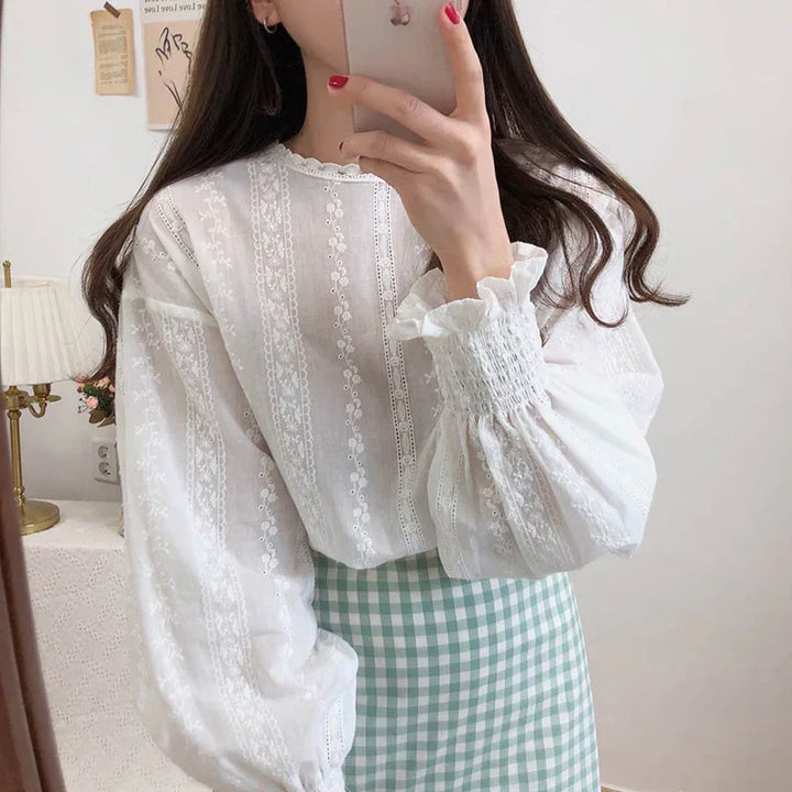 Woman in white lace blouse with puffed sleeves and green gingham skirt taking mirror selfie