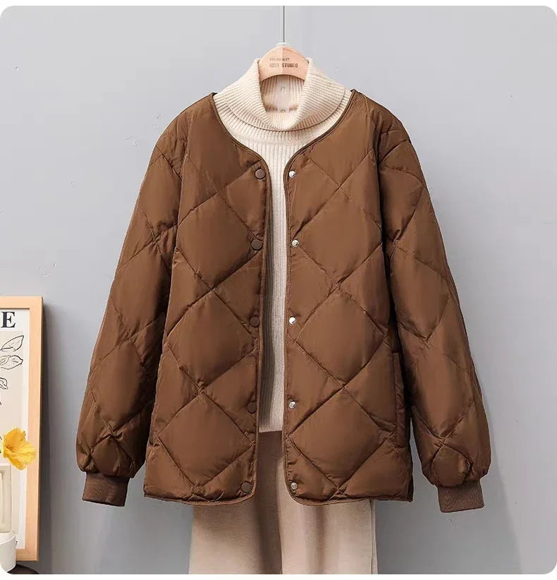 Brown quilted jacket over cream turtleneck sweater on hanger against gray background