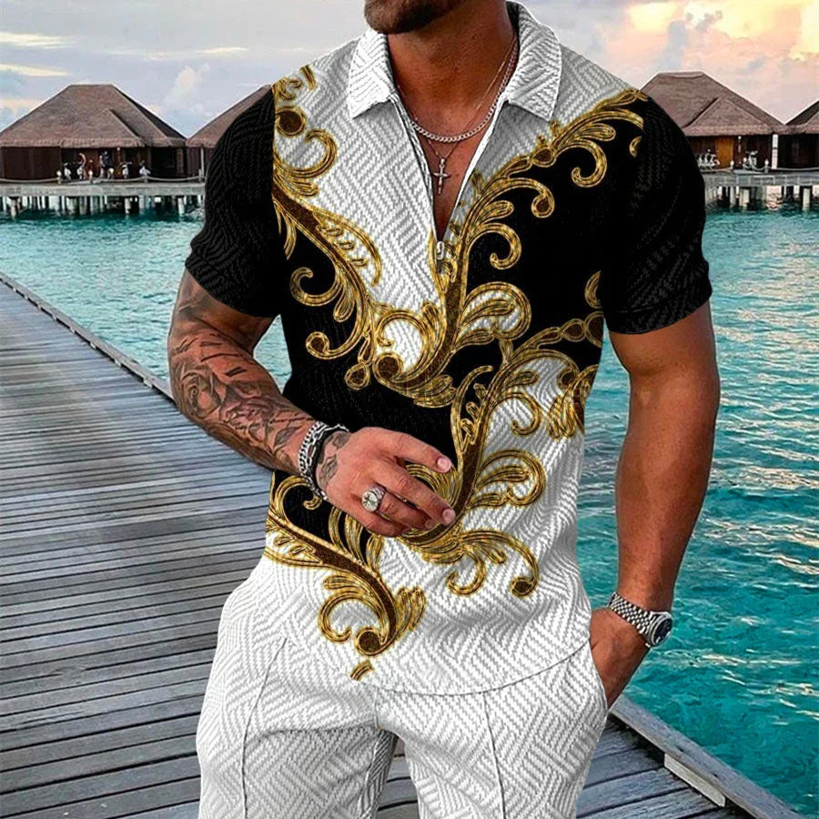 Man wearing black and white short sleeve shirt with gold baroque patterns standing on wooden pier by overwater bungalows