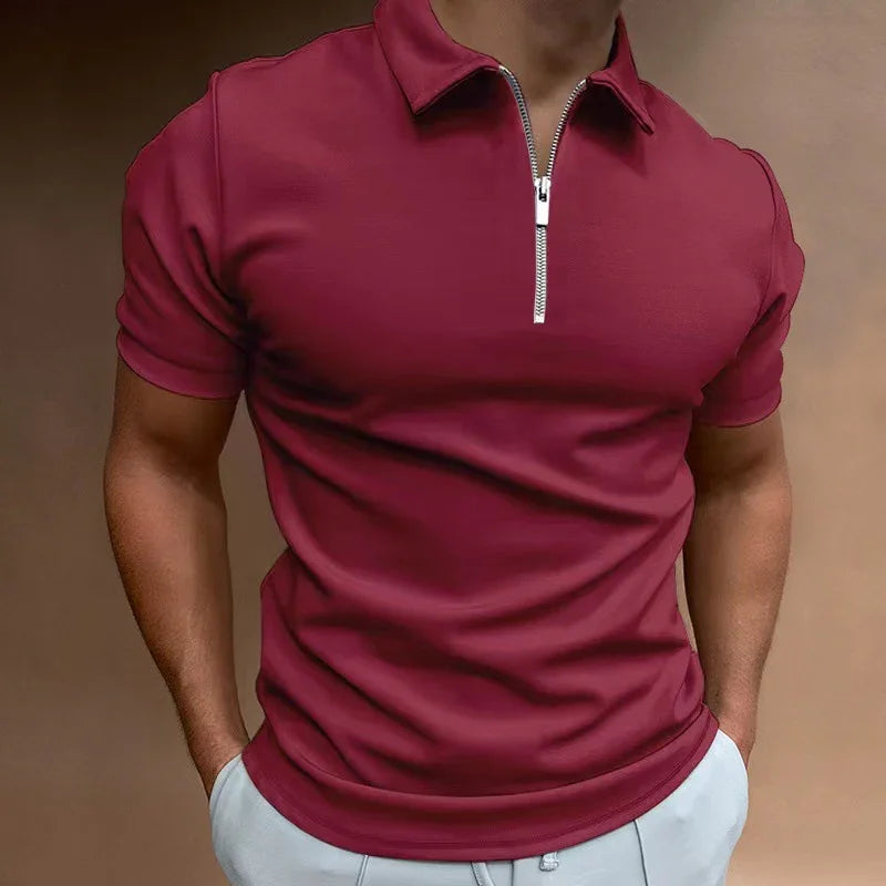 Man wearing fitted maroon polo shirt with front zipper and light gray pants in studio
