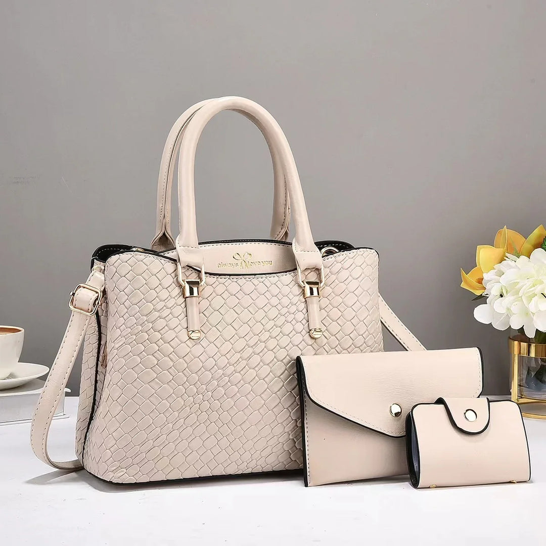 Beige textured handbag with gold hardware, matching wallet and purse on white surface