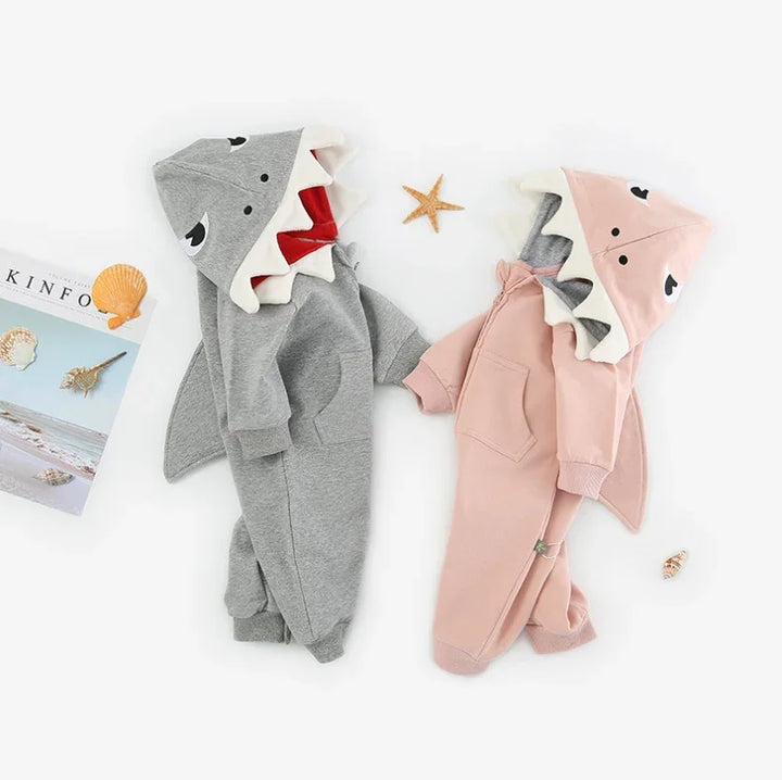 Gray and pink shark theme baby onesies with hoods featuring shark faces and fins, surrounded by seashells and starfish