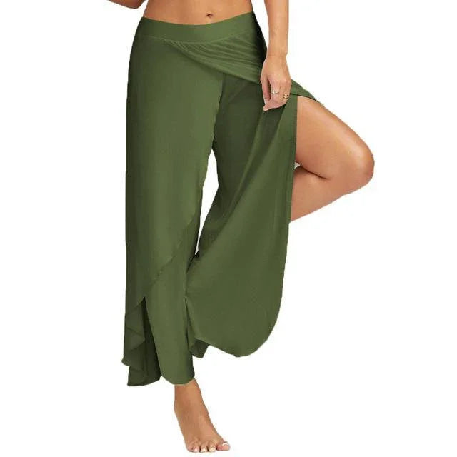 Woman wearing olive green wrap pants with side slit showing bare leg, barefoot on white background