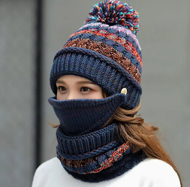 Woman wearing a navy blue knit winter hat with multicolor stripes and pompom, matching face and neck warmers