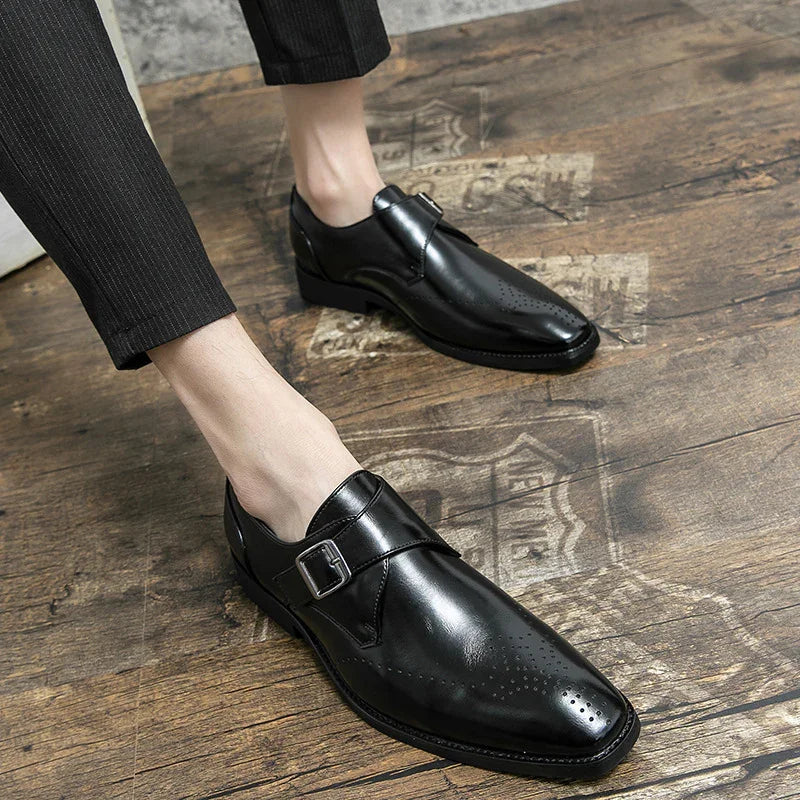 Mens black leather monk strap dress shoes worn with black pinstripe pants on wooden floor