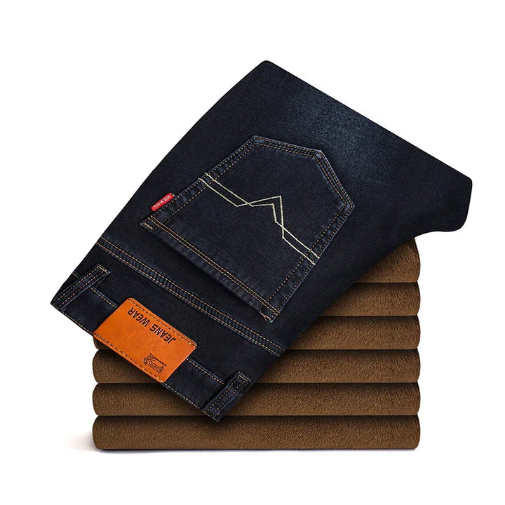 Folded dark blue jeans with brown leather patch on top of stacked brown fabric pieces