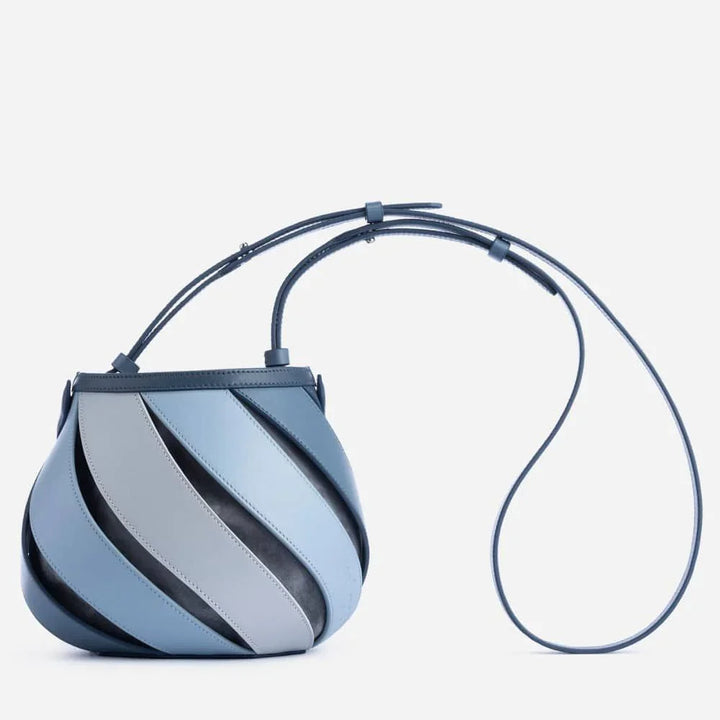 Modern small handbag with curved leather panels in blue and gray, featuring a long adjustable strap