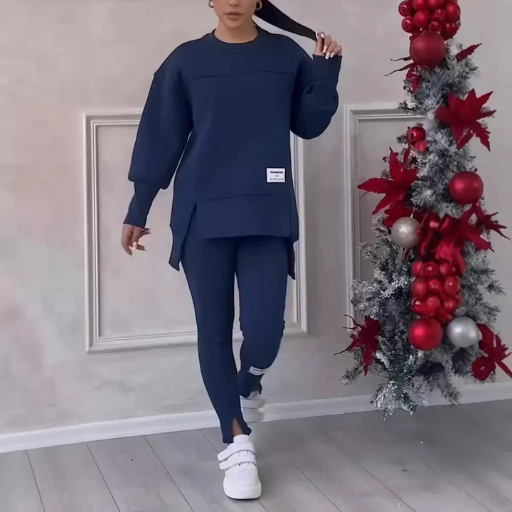 Woman in navy blue oversized sweatshirt and leggings with white sneakers near Christmas decorations