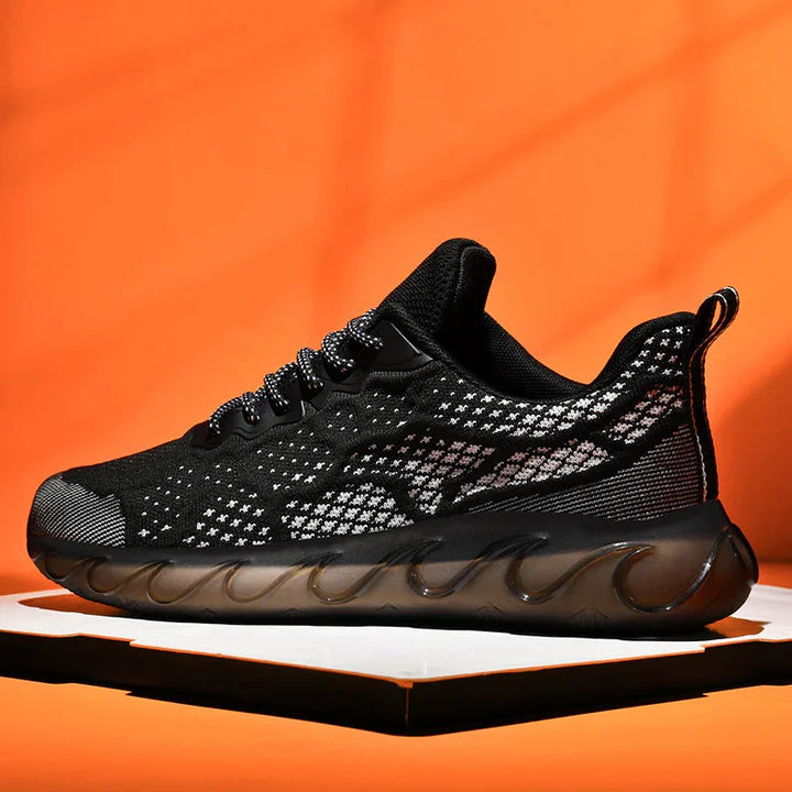 Modern black knit athletic shoe with patterned upper and translucent wavy sole on orange background