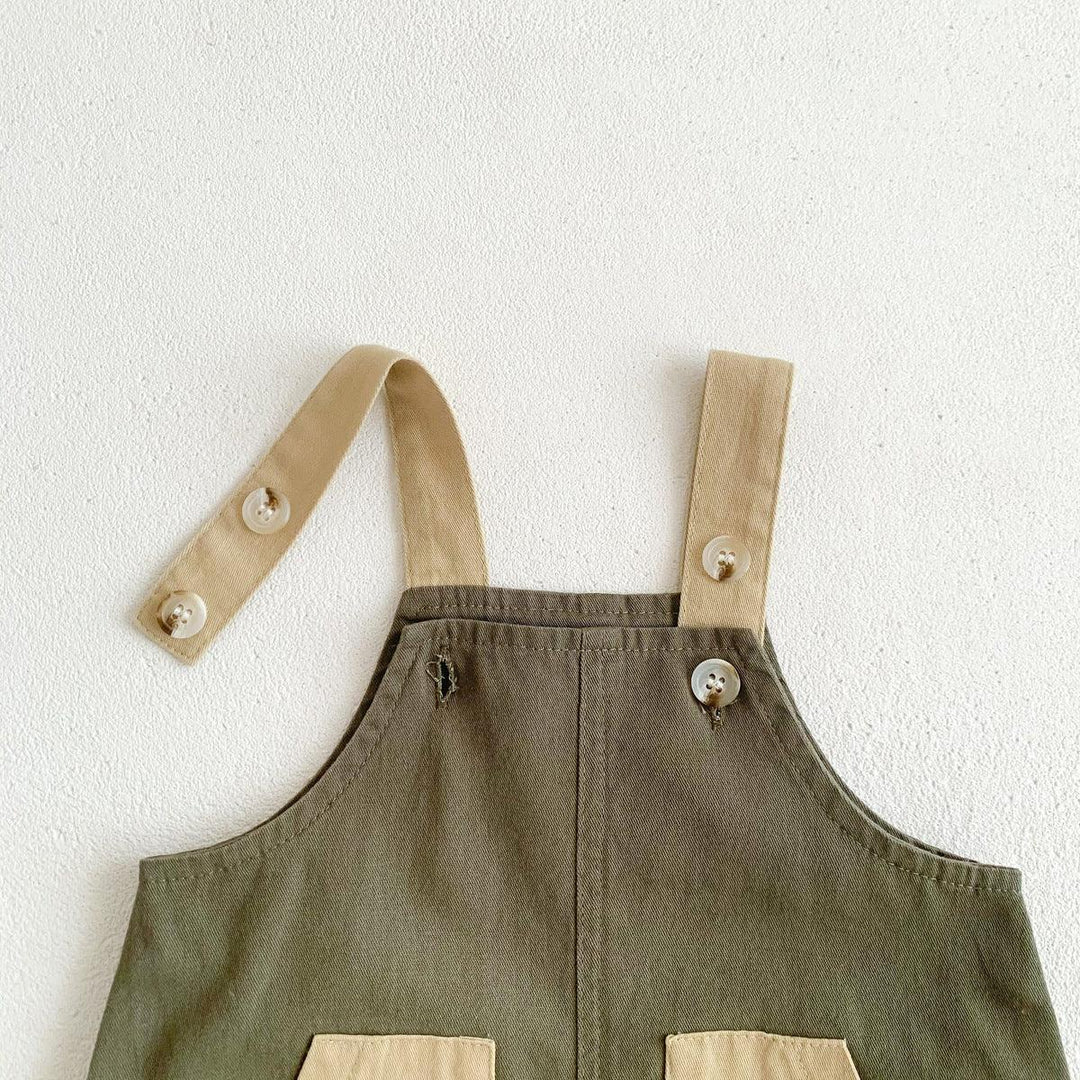 Olive green overalls with beige adjustable straps and button details on white textured background